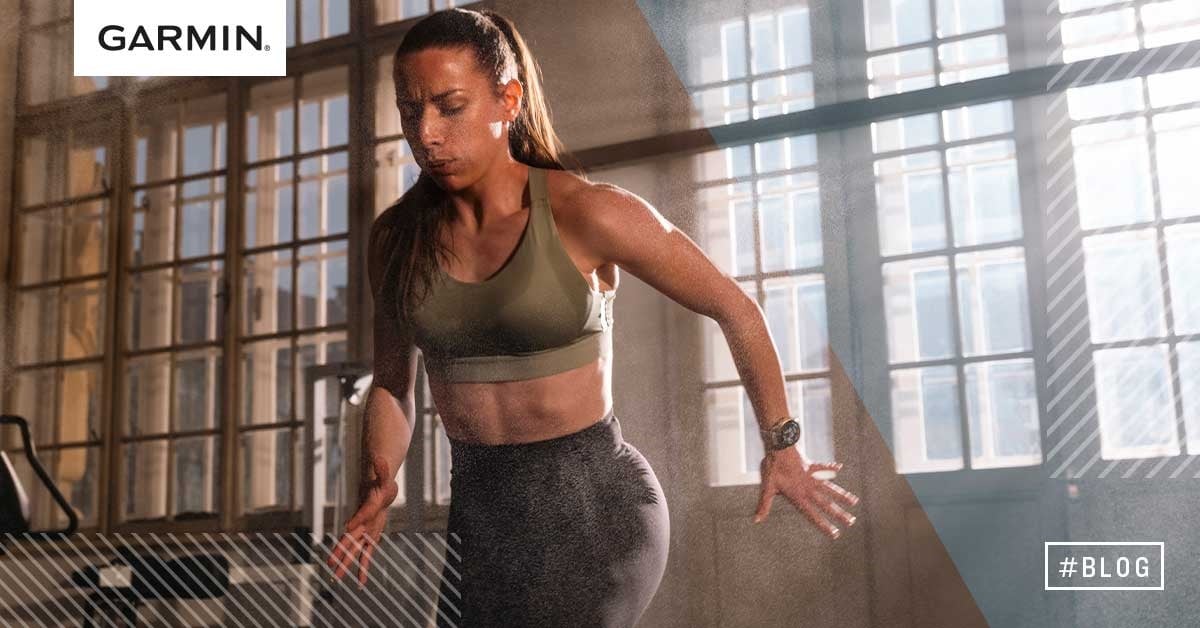Kvinna tränar intensivt för HYROX-tävling med Garmin-smartklocka, inomhusmiljö med naturligt ljus.