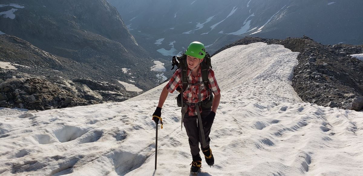 16-åring i grönt hjälmklättrar uppför snötäckt sluttning i Wind River Range