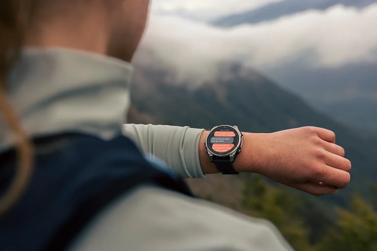 En person står i fjällmiljö och tittar på sin Garmin fenix som visar meddelanden på skärmen, i ett tydligt outdoor sammanhang.