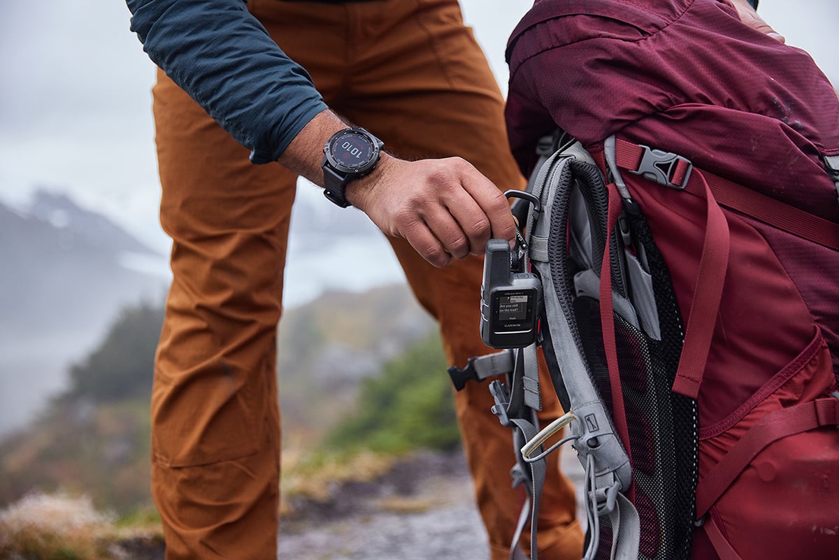 Person fäster en inReach®-enhet på en vandringsryggsäck inför turen